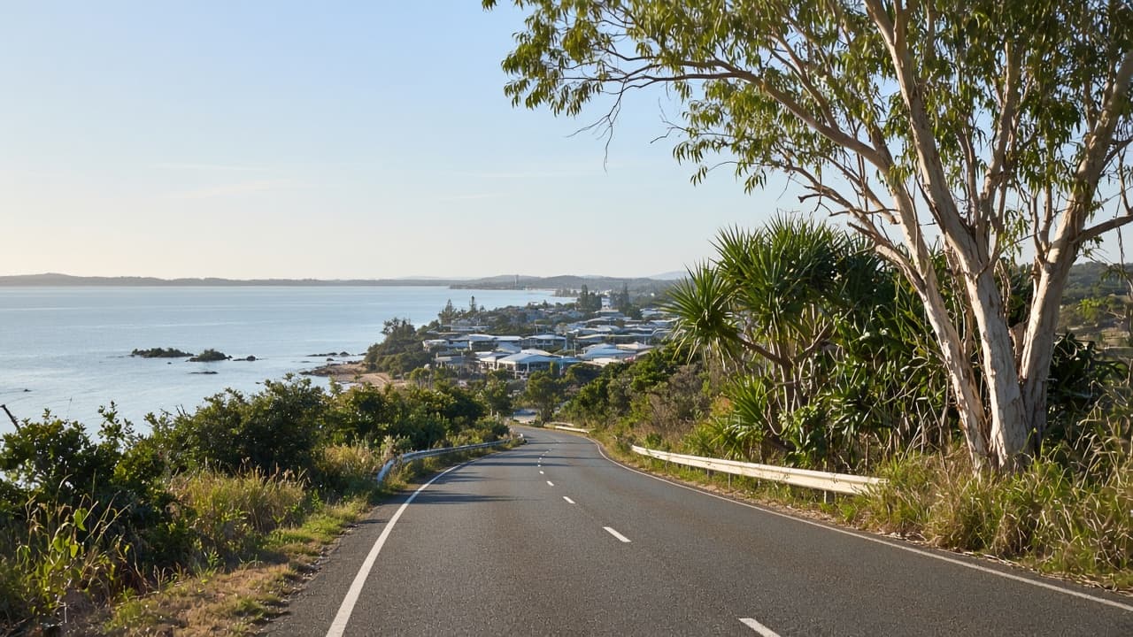 Coastal Queensland highway approaching a bay with paperbarks beside the road.